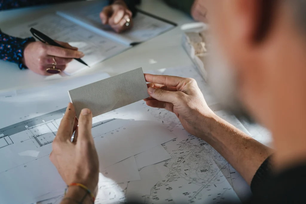 Architect holding a material sample over a set of drawings